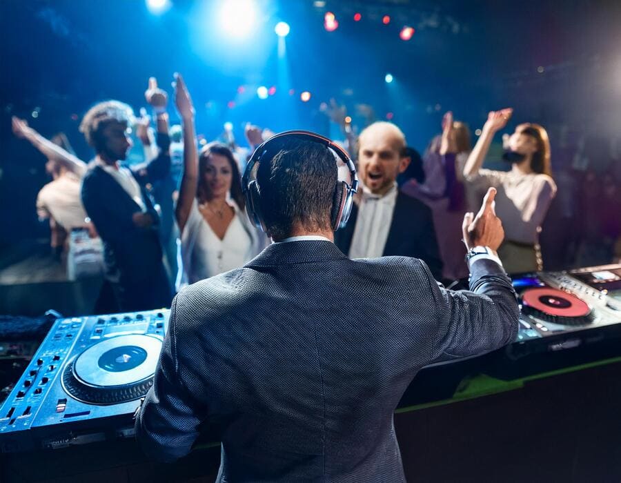 Firefly un dj en su cabina de espaldas, con gente entre los 30 y 40 años en una sala de fiestas oscu (1) fiesta empresa